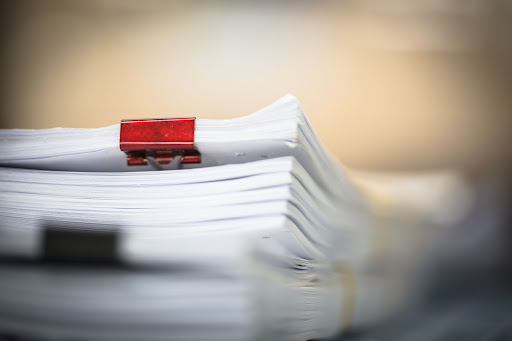 a stack of legal documentation held together with a red binder clip